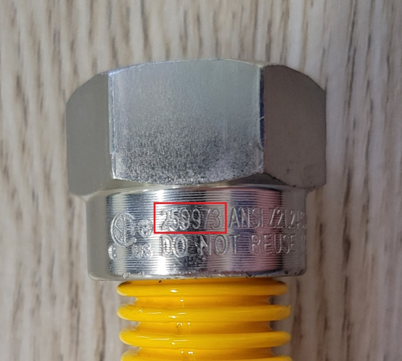 Close-up view of the flare nut on the recalled gas connector with CSA file number 