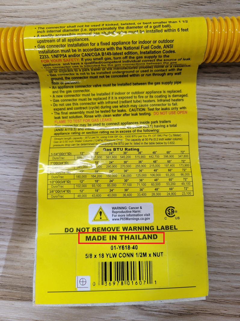 Close-up view of the yellow label on the recalled gas connector with 