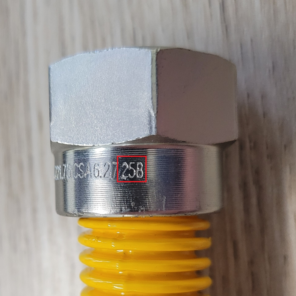 Close-up view of the flare nut on the recalled gas connector with date of manufacture engraving